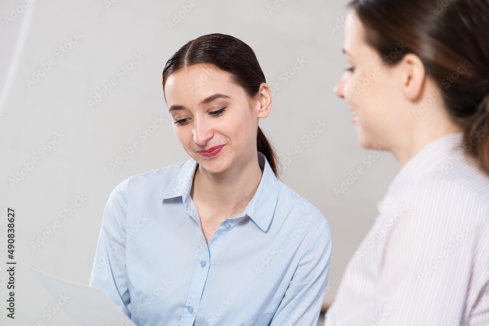 Young attractive woman talks to a colleague in the office