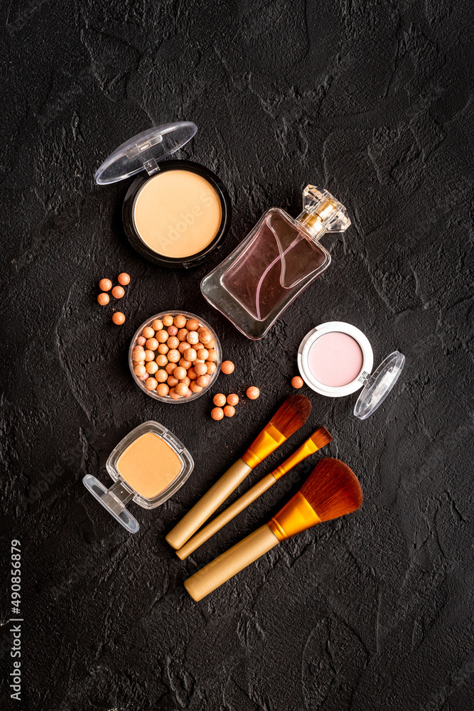 Makeup cosmetic products on black stone background, top view