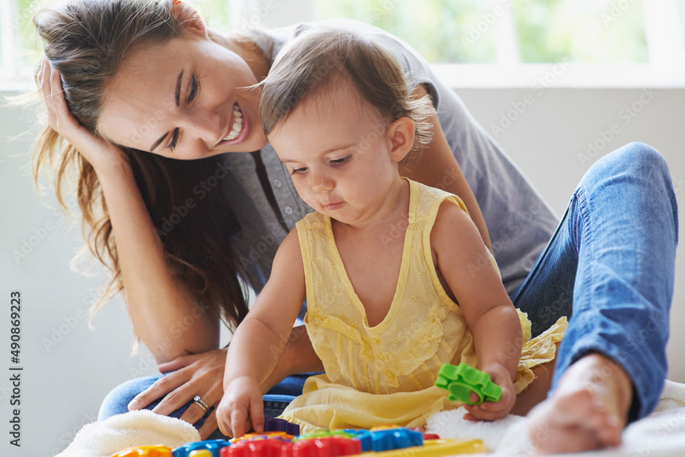 Shes a little genius already. Shot of a cute baby girl sitting on the floor with her mom and playing