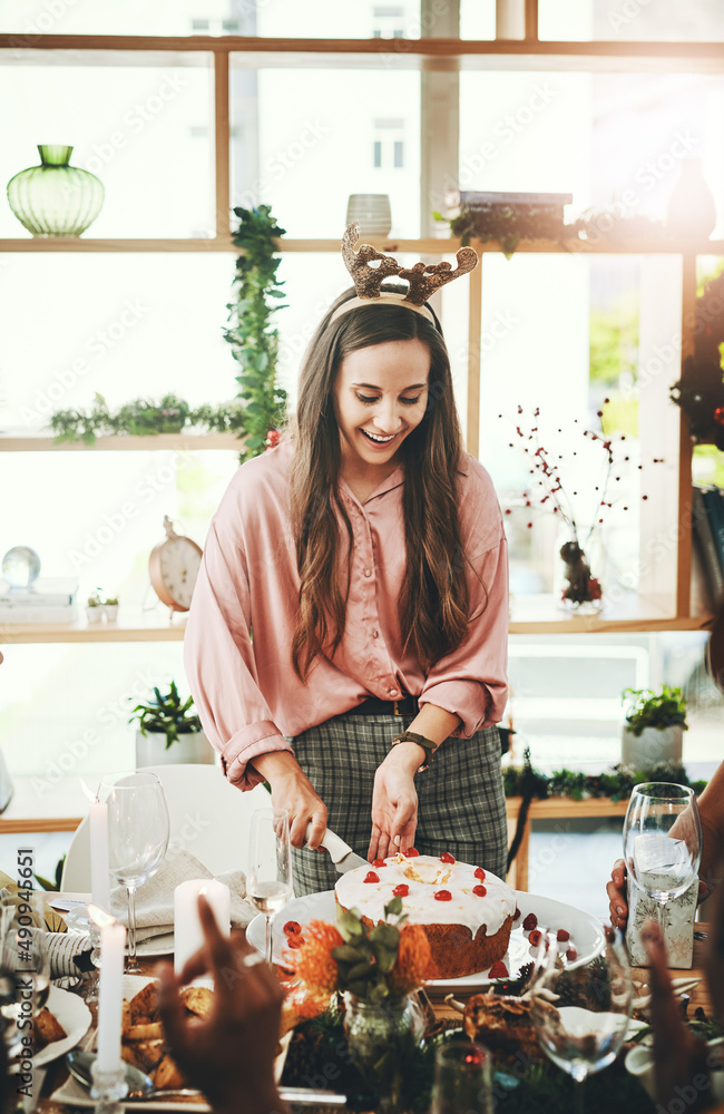 Guys Im cutting the cake. Cropped shot of an attractive young woman cutting the cake during Christma