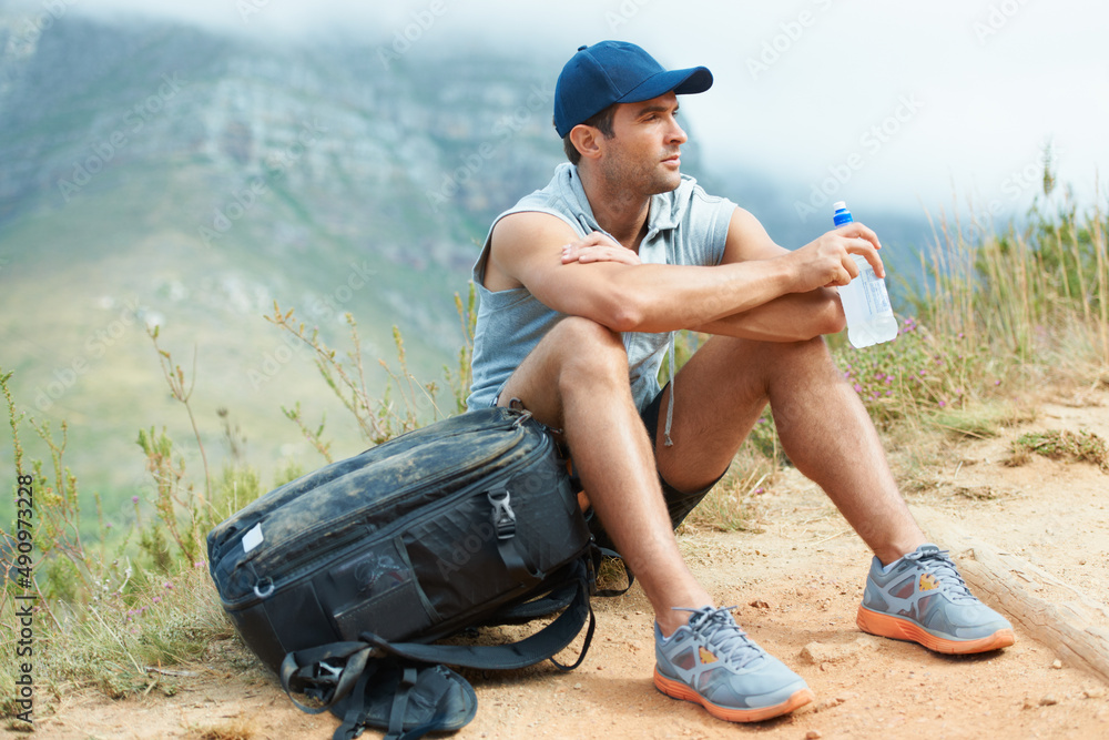 Taking a well-deserved break. Young hiker sitting down and taking a moment to rest.