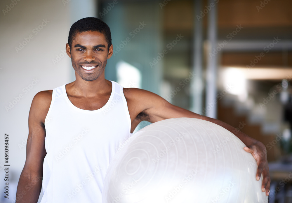 All I need for a great workout. Portrait of a smiling young man holding a fitness ball.