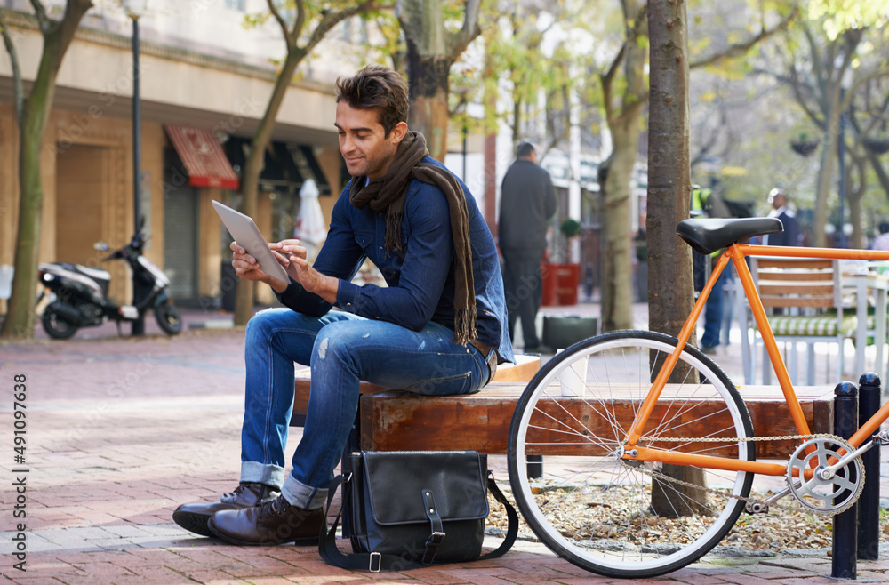 Relaxed city life moments. Shot of a man using his tablet while taking a break in the city with his 