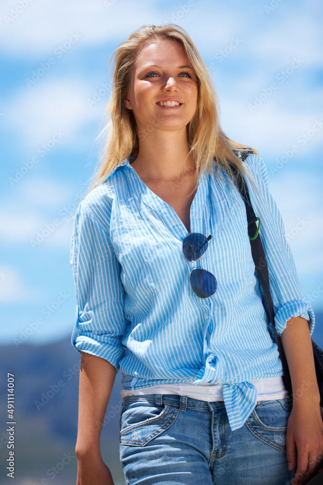 走进那边的狂野蓝色。美丽的年轻女子在明亮的蓝色夏日天空中行走。