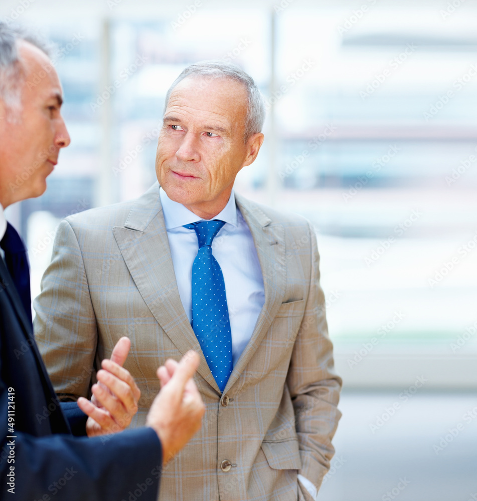 Two senior executives conversing. Two senior business men having discussion indoors.