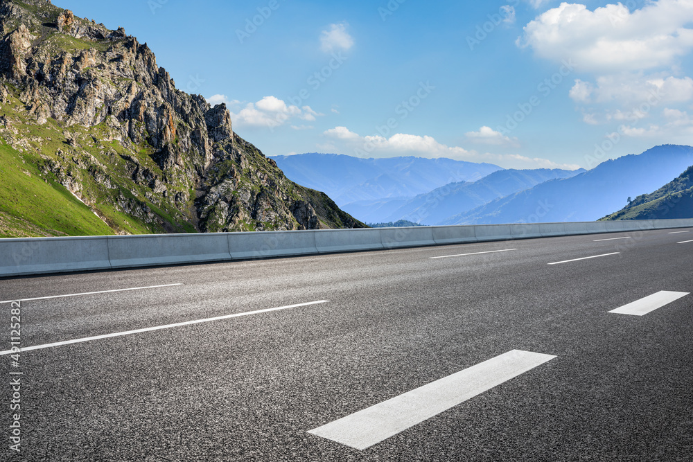 空旷的柏油路和蓝天下的山地自然风光。道路和山地背景。