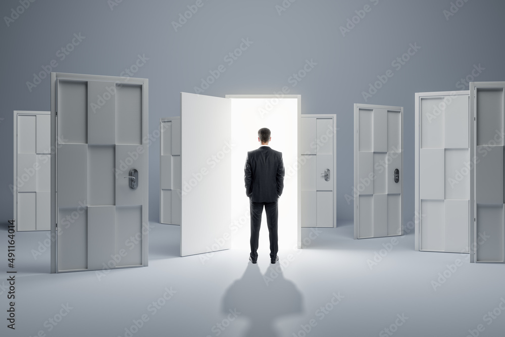 Businessman standing in front of abstract white puzzle door in interior. Future, choice, success, di