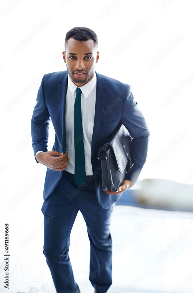 On his way to a meeting. A handsome african american businessman walking up the stairs while carryin