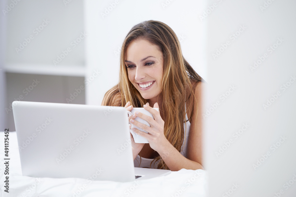 Connected from the comfort of home. A beautiful woman using her laptop from the comfort of her bed.