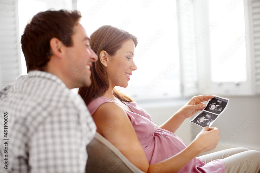 Our first look at our baby. Happy young couple looking at a image of their babies sonogram.