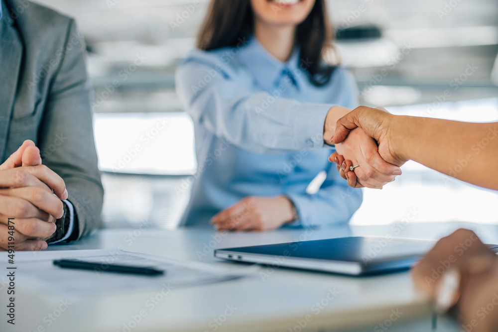 Close-up photo of two female colleagues shaking hands.