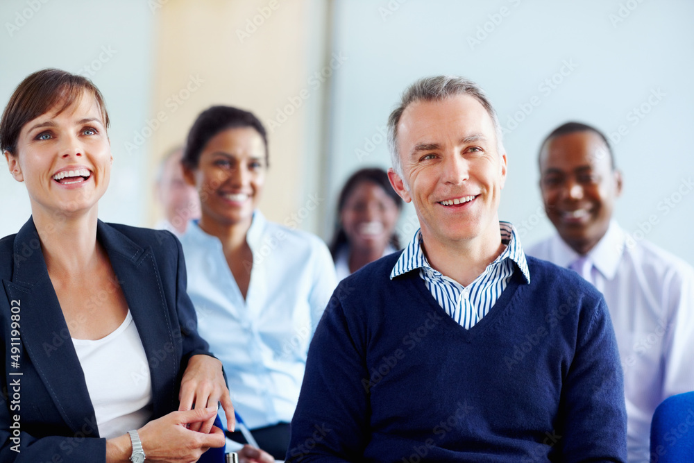 Executives smiling while listening presentation. Group of executives listening to presentation.