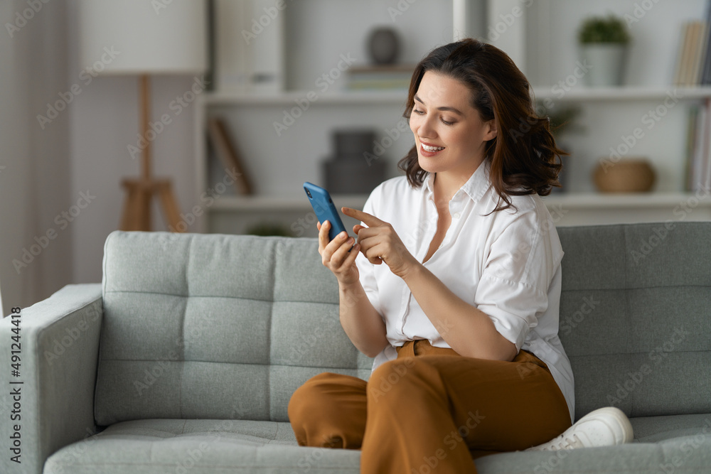 woman is using a phone sitting on a sofa