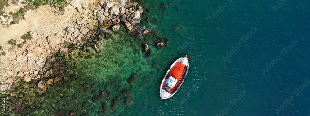 Aerial drone ultra wide top view photo of traditional red fishing boat anchored in exotic Ionian des