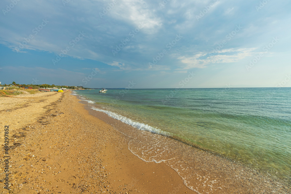 Beautiful view of shore line on bright summer day. Sandy coast line and blue sea water merging to bl