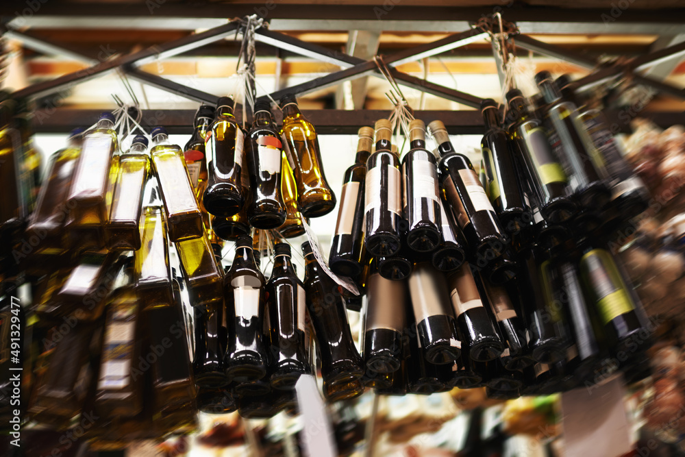 Only the best olive oil. Hanging bottles of olive oil at a food market.