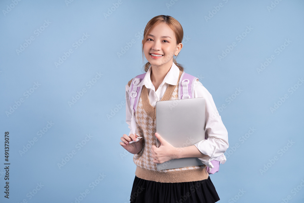 Young Asian high school girl on blue background