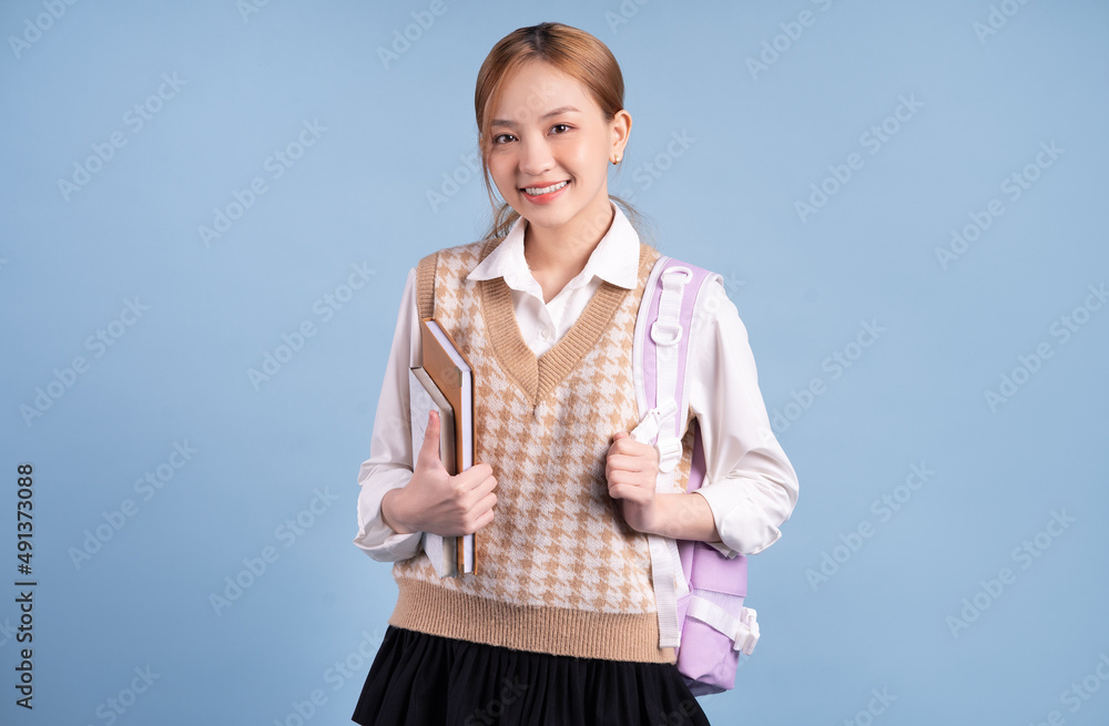 Young Asian high school girl on blue background