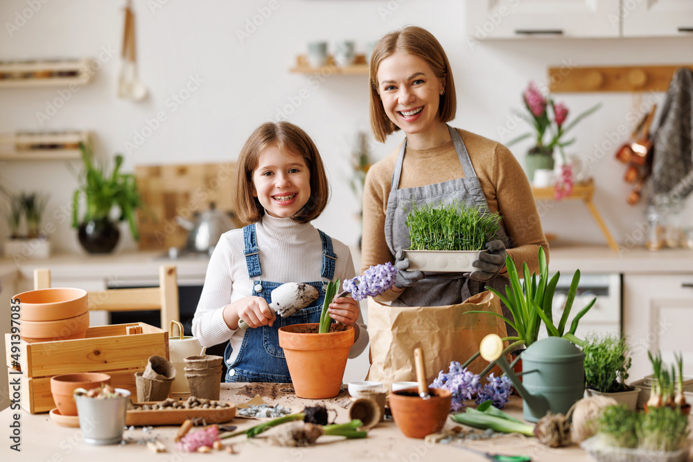 Optimistic mother and daughter with flowers in kitchen