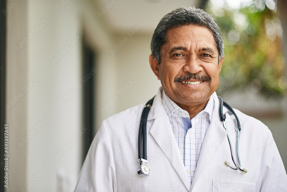 Happy to help you recover. Portrait of a mature male doctor standing outside.