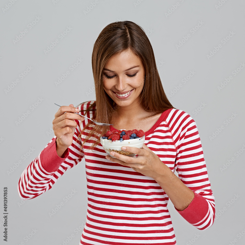 Getting into a bowl of goodness. Studio shot of an attractive young woman eating a bowl of berries o