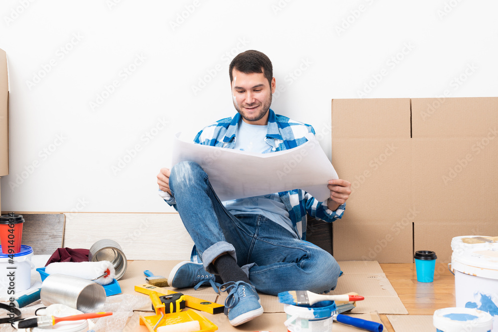 Guy looking at paper blueprint while sitting