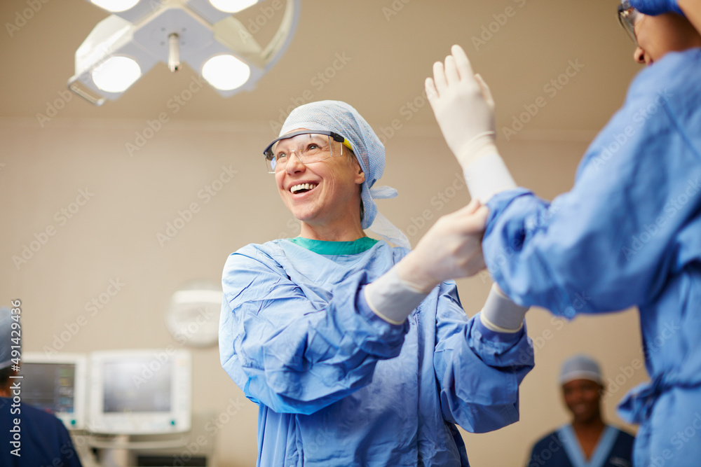 Protecting themselves against germs. Shot of surgeons putting on surgical gloves in preparation for 