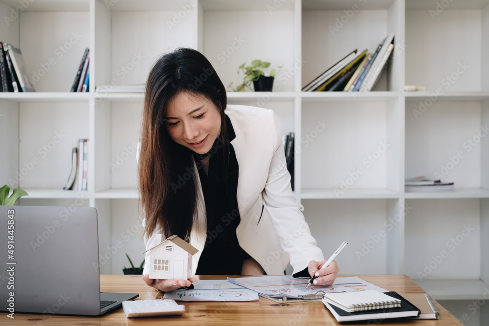 一名妇女持有并检查房屋模型。房地产房屋评估和检验保险c