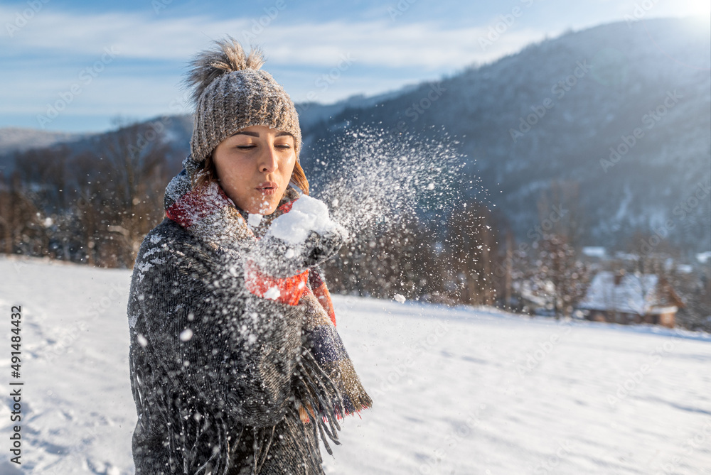 Beautiful girl blowing snow happy winter time