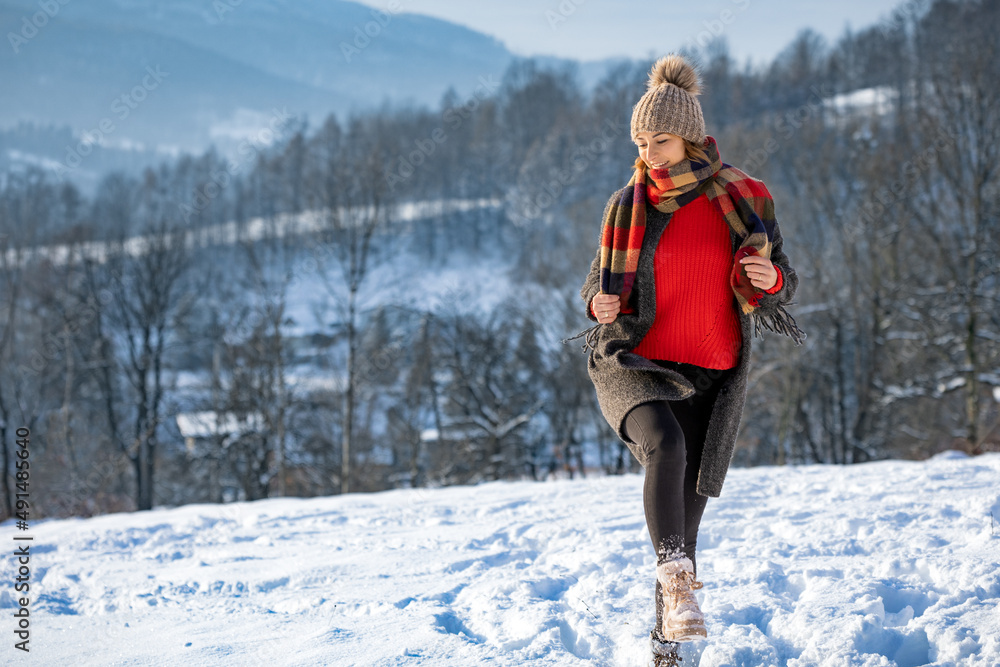 Young woman in the winter time walks among snow