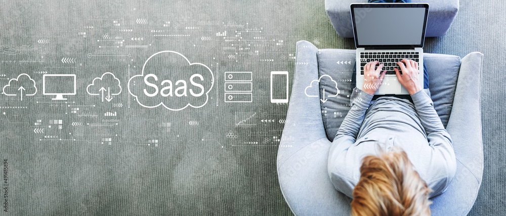 SaaS - software as a service concept with man using a laptop in a modern gray chair