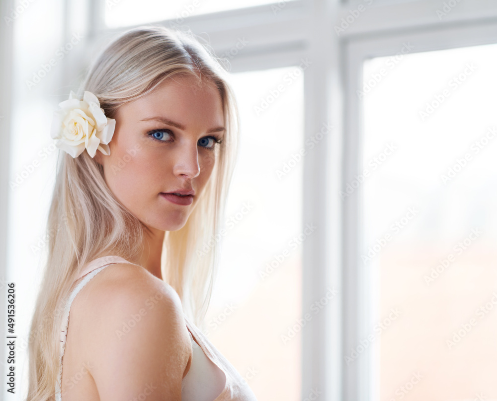 Beauty and pureness. Portrait of an attractive woman with a white rose in her hair while standing in