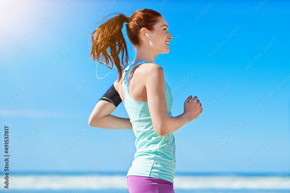 Focused on fitness. Cropped shot of a young woman running on the beach.