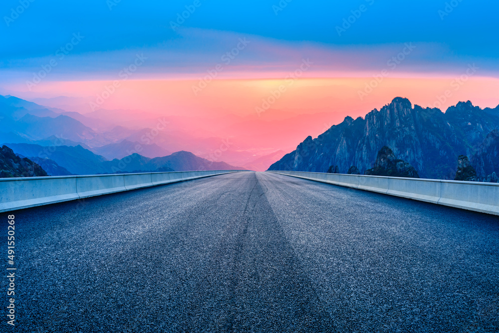 日落时笔直的道路和山脉自然风光。道路和山脉背景。