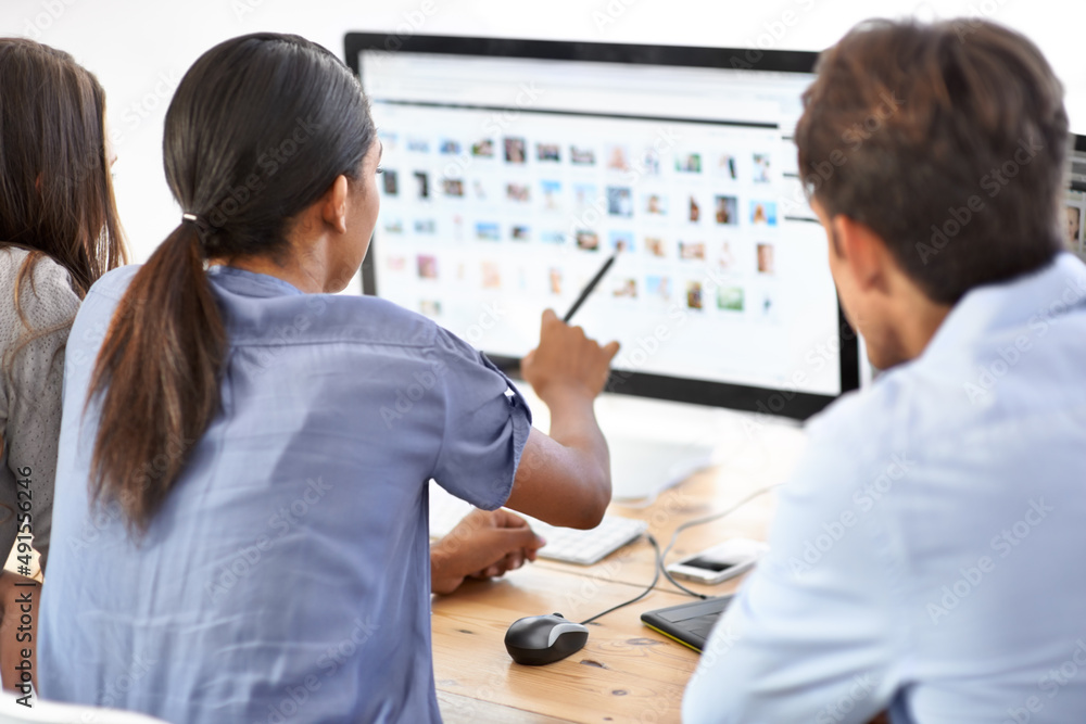 Working together to meet your design needs. Three young editors looking at photos in their office.