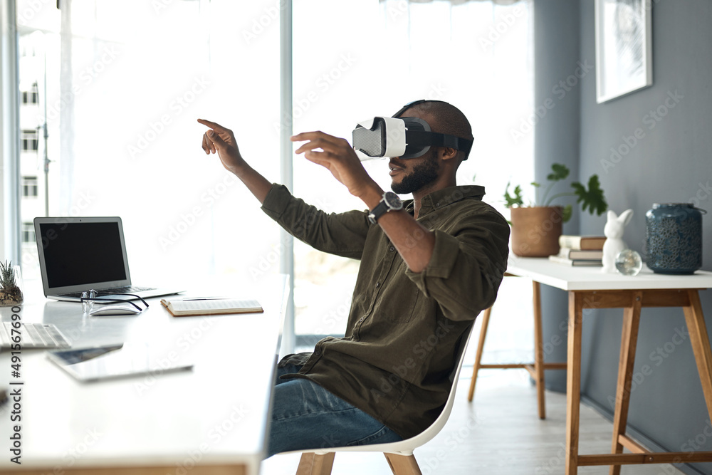 Tomorrows world is created today. Shot of a young businessman using a virtual reality headset in a m