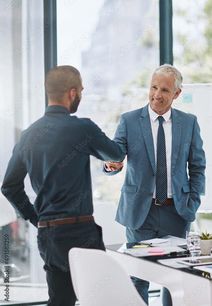 Congratulating him on a job well done. Cropped shot of two businessmen shaking hands in the office.