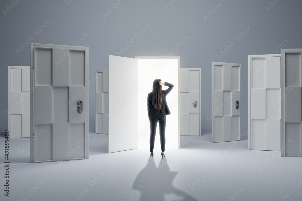 Businesswoman standing in front of abstract white puzzle door in interior. Future, choice, success, 