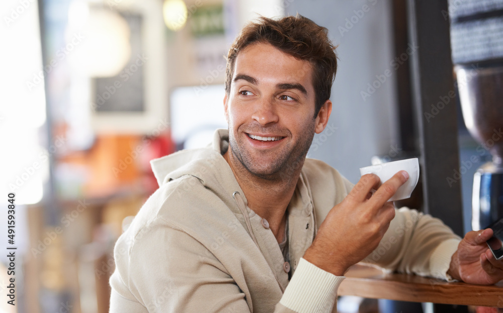 Getting my daily dose of coffee. Shot of a handsome young man drinking a coffee in a cafe.