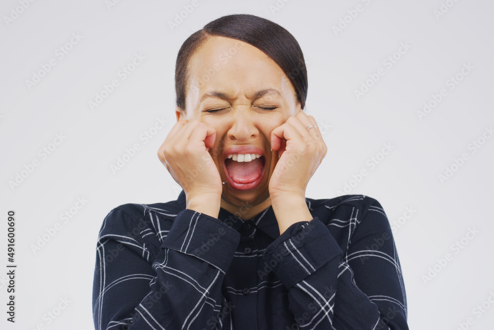 Can you hear me. Studio shot of a young woman crying while standing against a gray background.