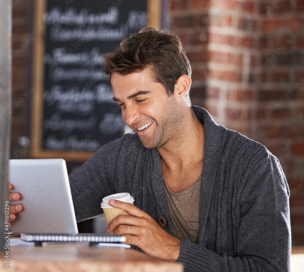 Great wifi and good coffee. A young man working on a digital tablet holding a coffee in a restaurant