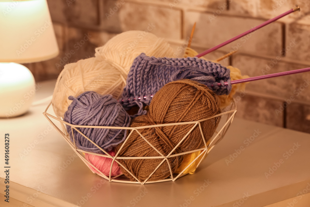 Basket with different knitting yarn on table, closeup