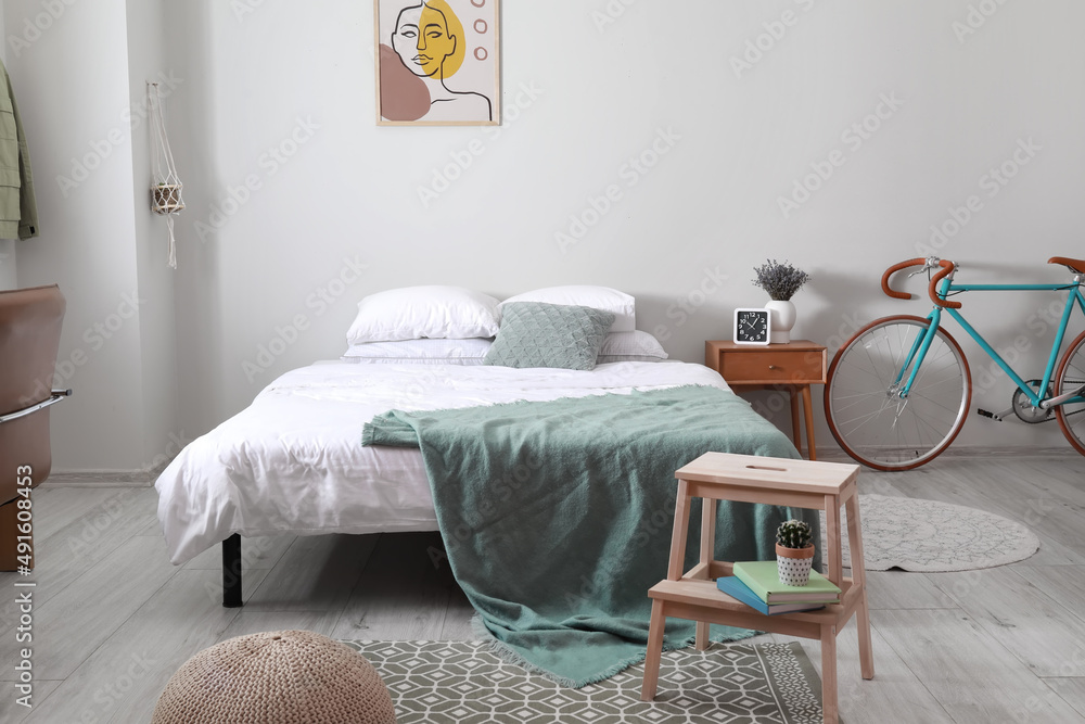 Interior of light room with bed, bicycle and step stool