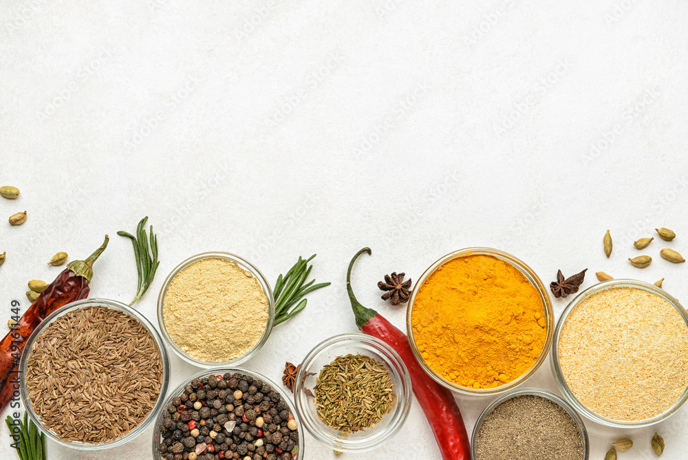 Composition with glass bowls of aromatic spices on light background