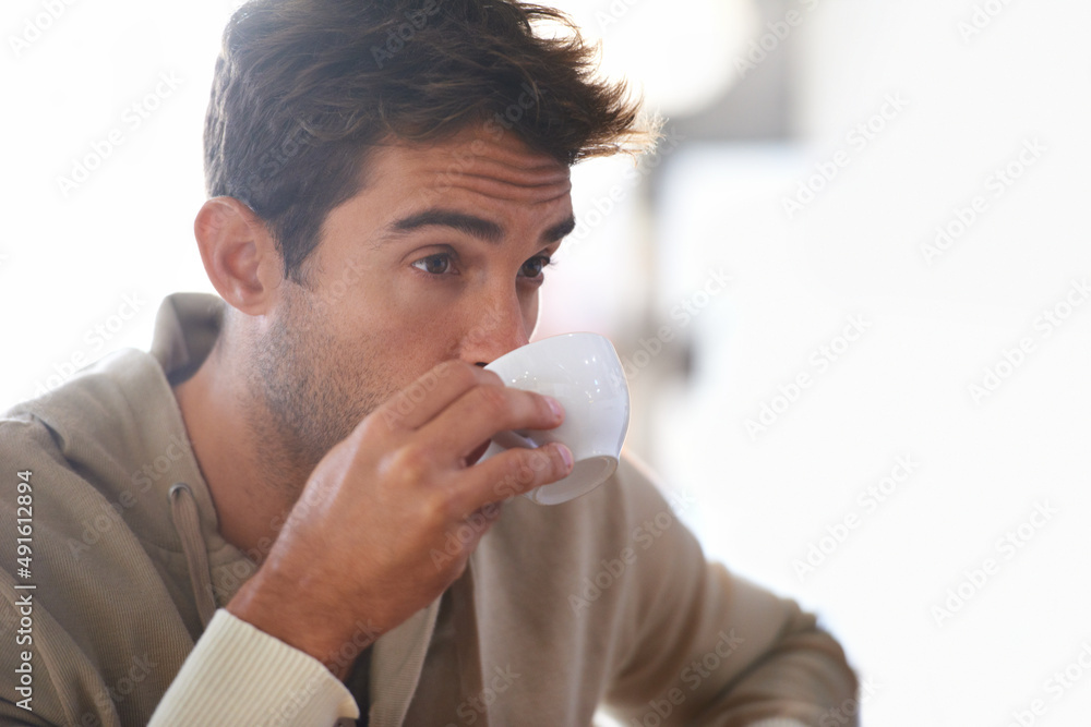 Getting my daily dose of coffee. Shot of a handsome young man drinking a coffee in a cafe.