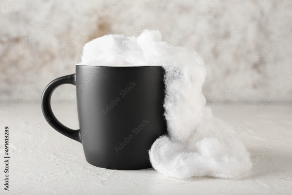 Cup with soft cotton wool on light background