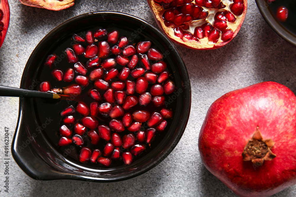 Bowl of pomegranate molasses and fresh fruits on light background