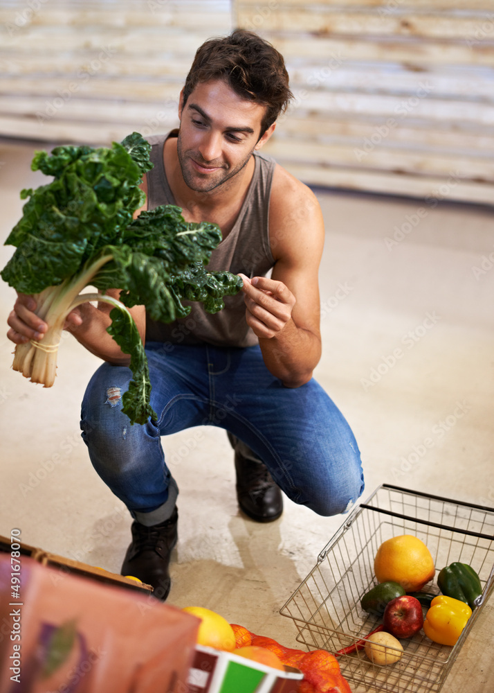 I only buy the freshest. Shot of a young man choosing which head of spinach to buy.