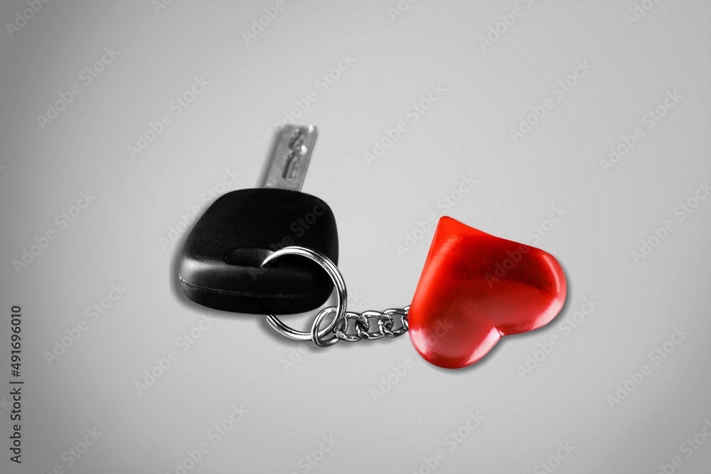 Car key with keychain and heart on gray background