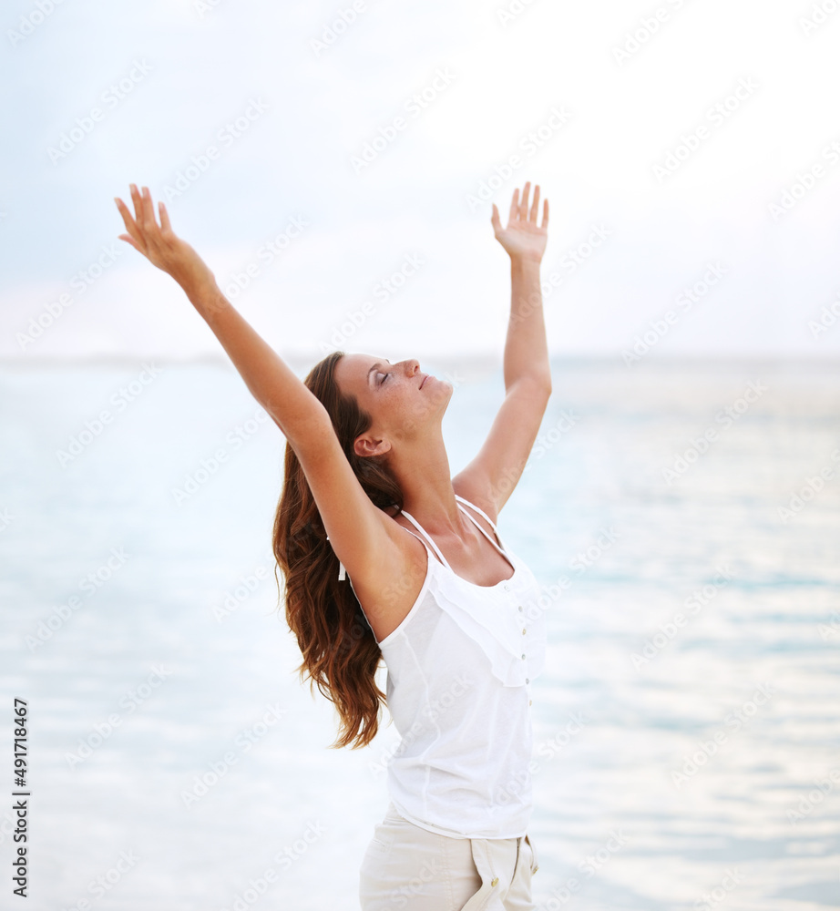 Finding release. Shot of a beautiful young woman with her arms raised to the sky.